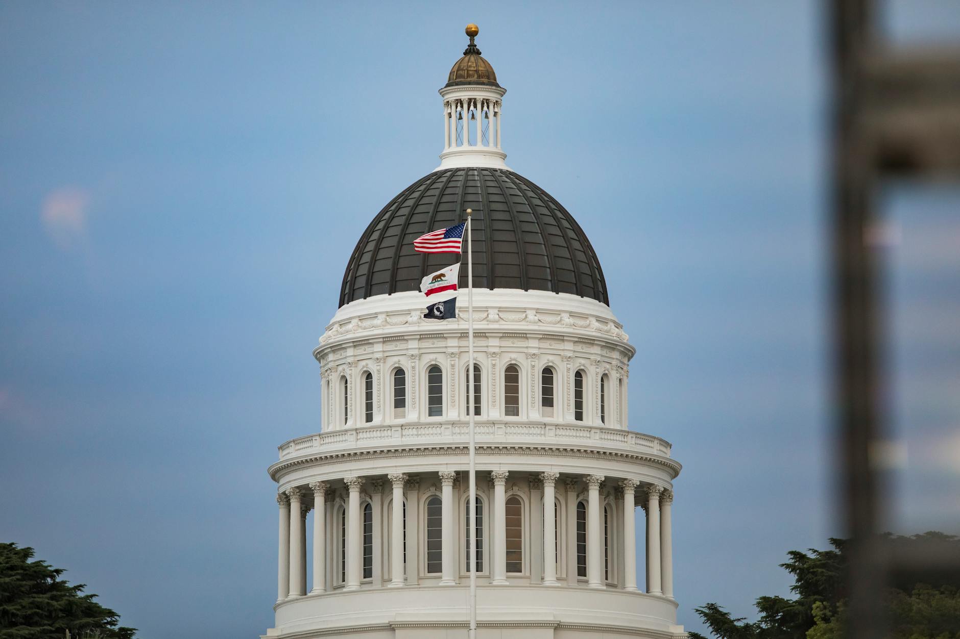 View of California State Capitol dome with American and state flags.
