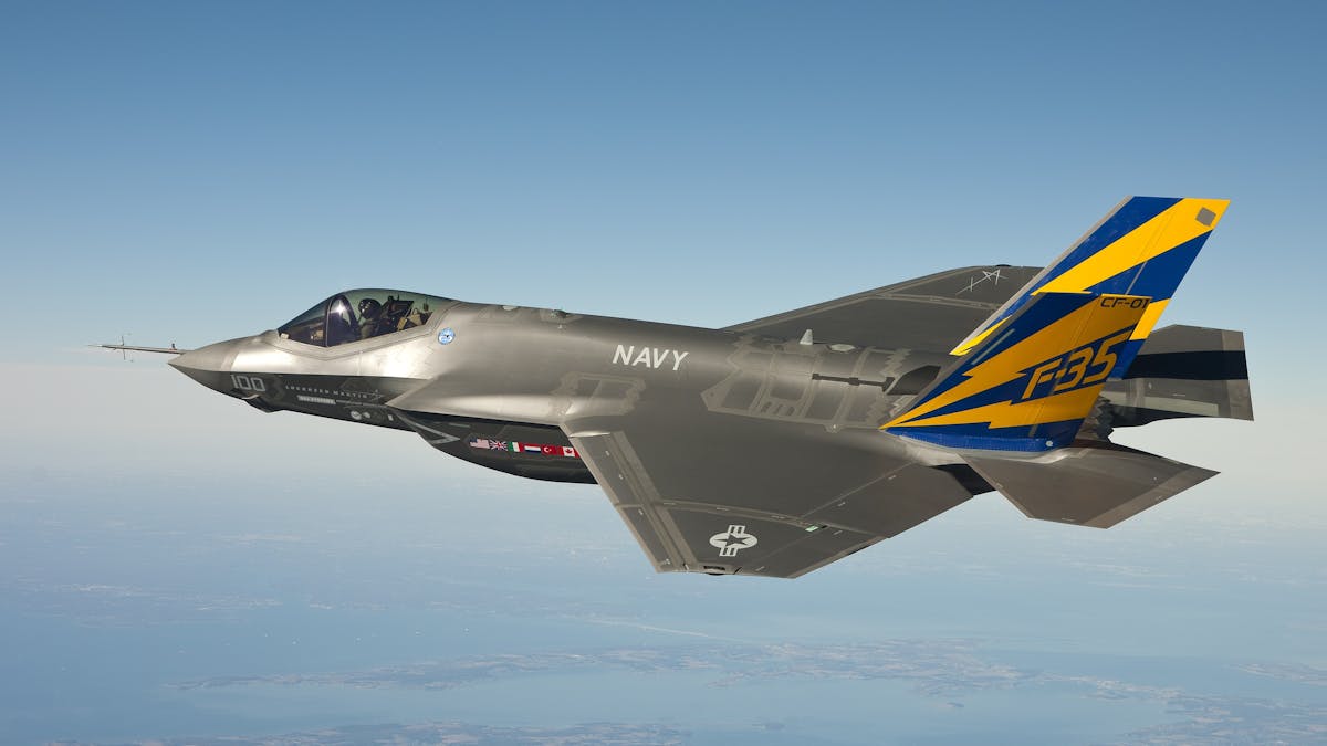 F-35 fighter jet soaring through clear skies over a military installation